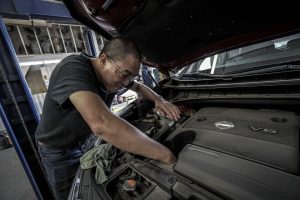 Car Mechanic working under the hood. 