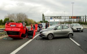 Car Accident with a red car flipped over lying upside down. 