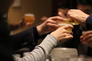 Several people toasting drinks at a bar. 