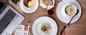 Picture of a table with breakfast food and a laptop. 