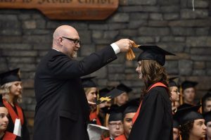 High School Graduate walking across the podium shows the need for talking with an insurance agent about how best to insure your college student. 