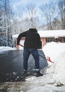 Man Shoveling Snow at his house after a Winter Weather Storm.